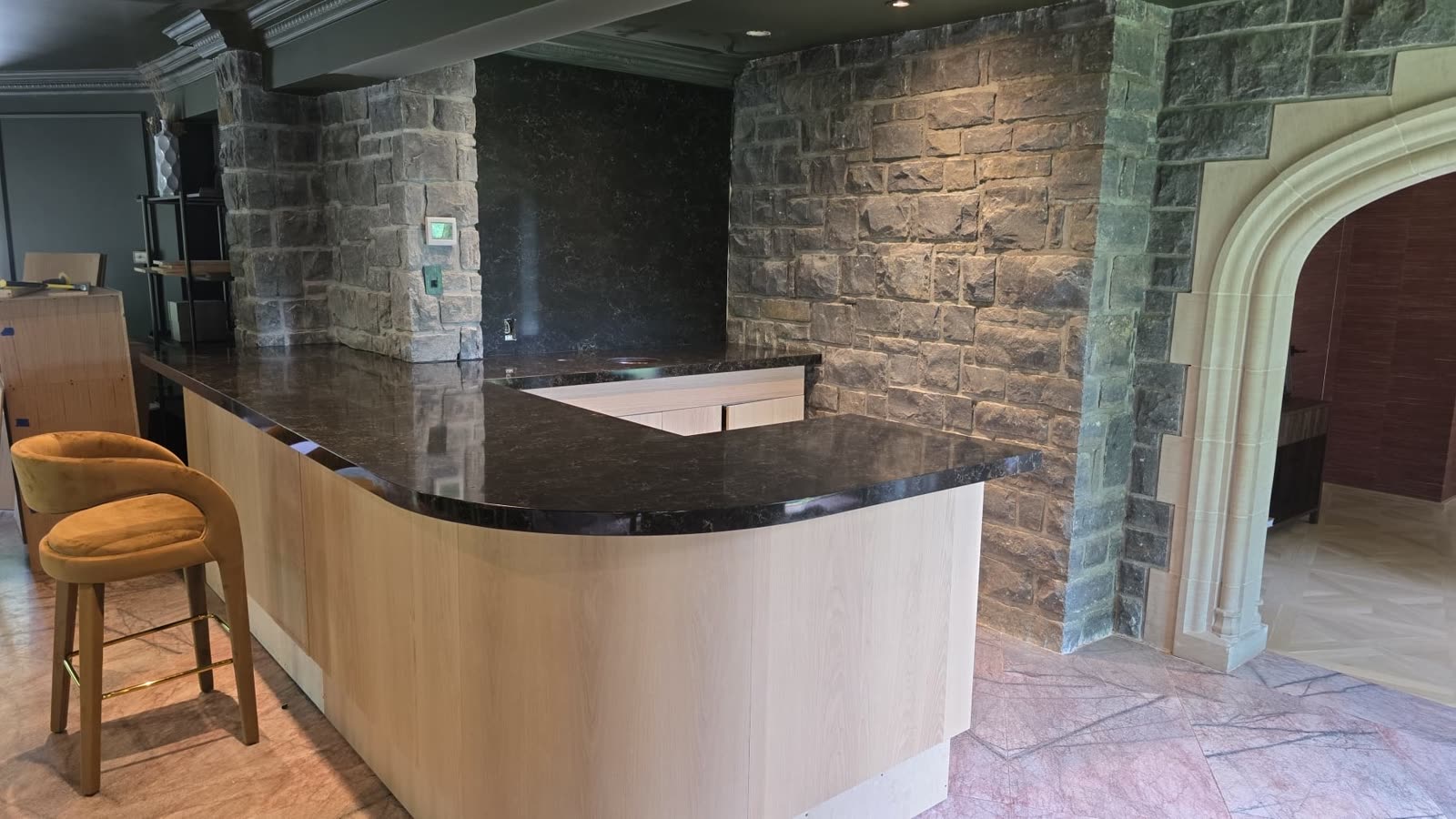 Bar en granite foncé sur mur de pierre par Granite Royale